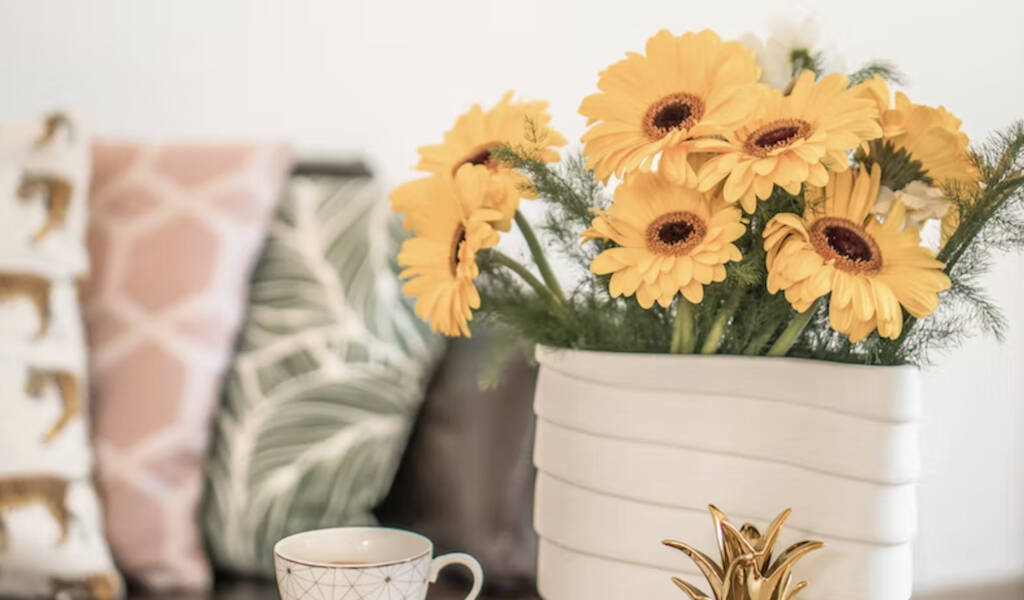 A table with books, sunflowers in a vase and tea cup in a stylish living room.